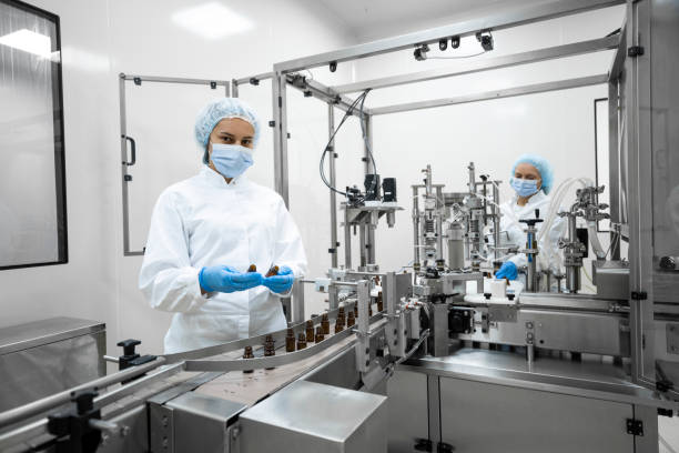 Scientists in protective gear working in a sterile laboratory with automated machines.